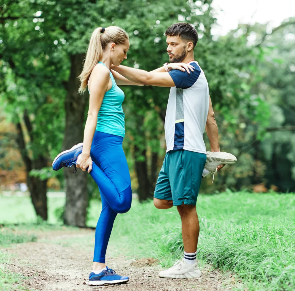 athletic couple warming up and stretching in park utc
